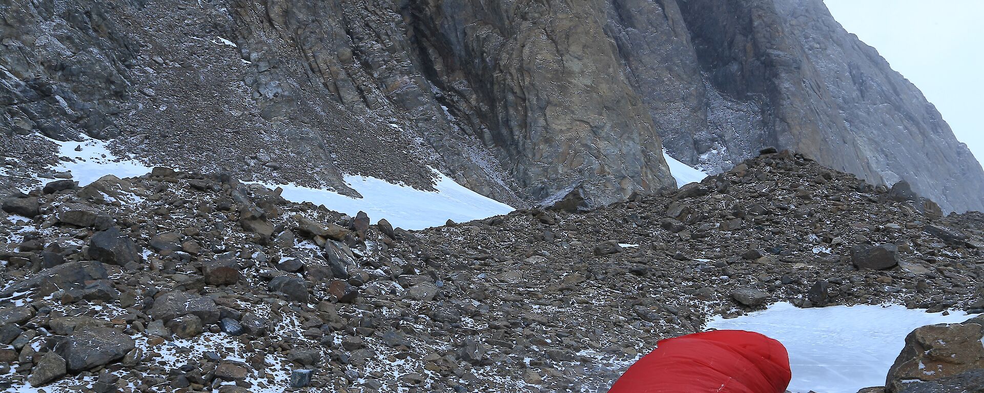 A red bivy bag on the rocks will keep you alive in bad weather