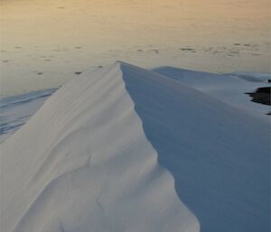 A mound of snow from the last blizzard and in the distance the harbour freezes