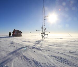 A bright orange Hägglunds oversnow vehicle and the automatic weather station