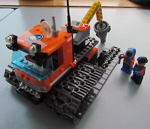 Lego men repairing an oversnow vehicle