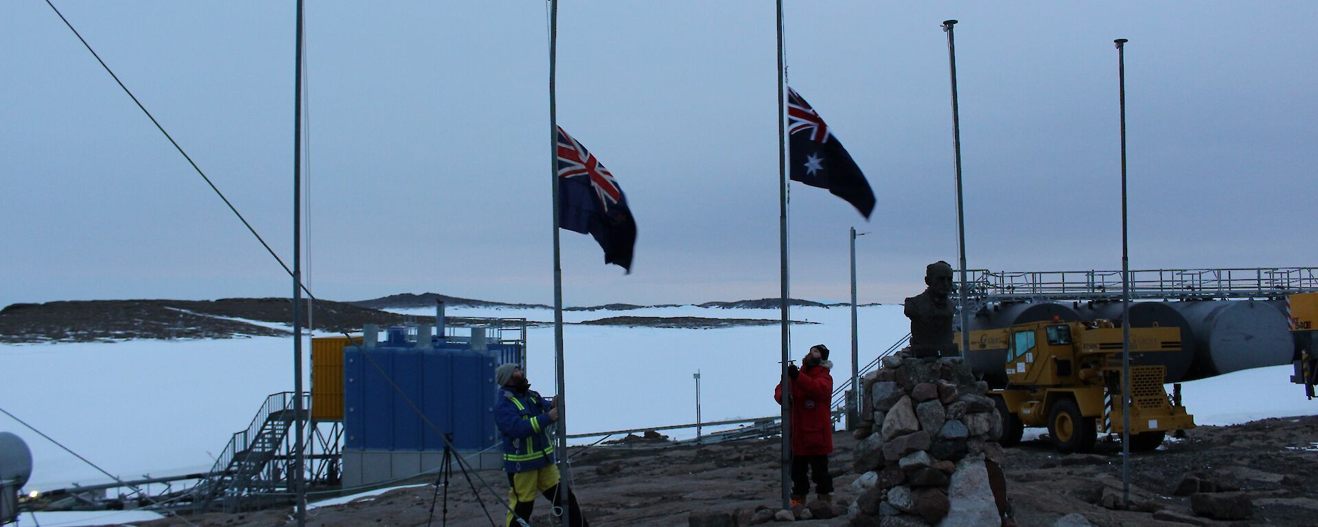 In the dim light of dawn the Australian and New Zealand flags are at half mast