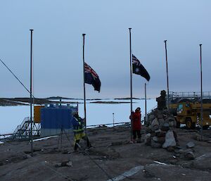 In the dim light of dawn the Australian and New Zealand flags are at half mast