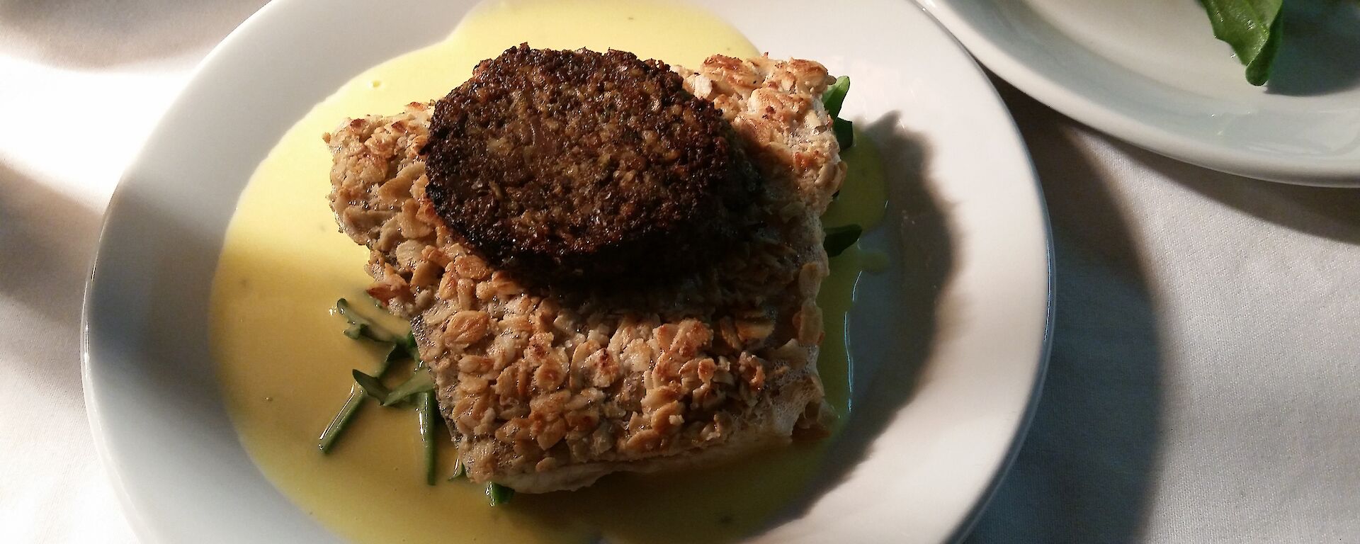 Main course of Barramundi coated in oatmeal topped with black pudding