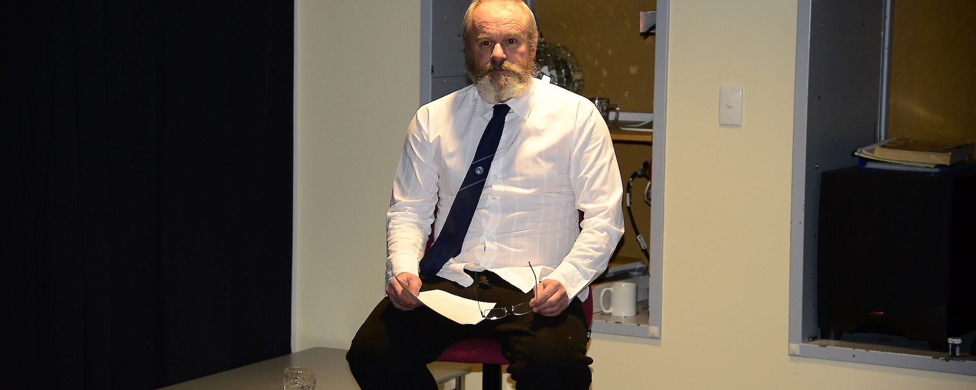 Pete the poet sitting on a chair reciting the poem he produced about each of the expeditioners