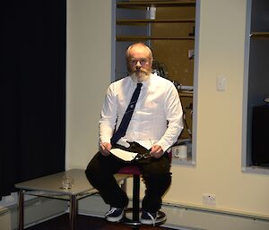 Pete the poet sitting on a chair reciting the poem he produced about each of the expeditioners