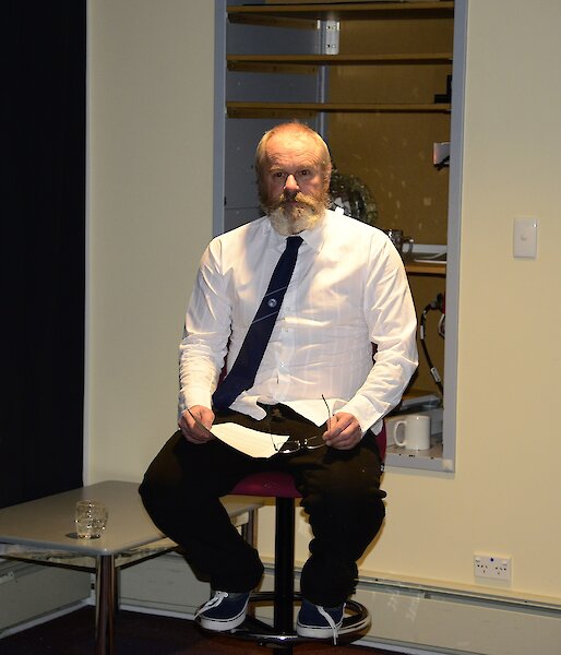 Pete the poet sitting on a chair reciting the poem he produced about each of the expeditioners