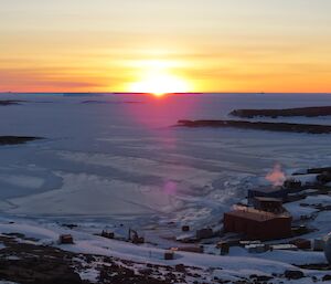 Sunset over the sea ice, the colours are shades of orange and yellow.