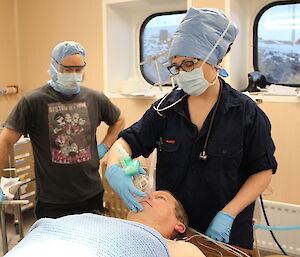 Expeditioners give oxygen to pretend patient John during training.