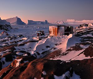 The two huts at Macey Island nestled amongst rocks and snow.