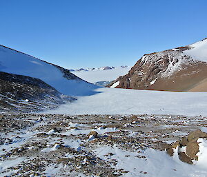 View of the plateau from Fang hut with hills covered in dirt, rocks and snow.
