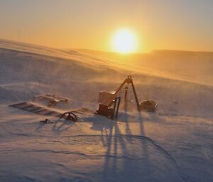 Snow covers up large pieces of equipment stored outside.