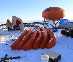 Triangular panels of a hut lie in the snow ready to be assembled