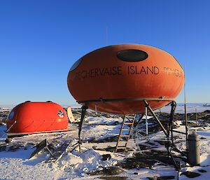 A spaceship like hut used as a lab sits in front of a new melon shaped hut. In the distance are the mountains of the David Range.
