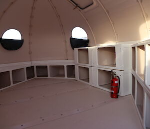 Inside the new round new melon hut, two porthole windws are seen, a fire extinguisher and lots of storage cubbies.