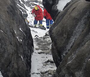 Through a gap in rocks, an expeditioner is preparing to clean camera one