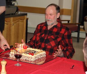 Male expeditioner is presented a cake. He looks excited.