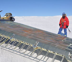 Trev standing by the wing of the aircraft of the aircraft which is upside down..