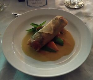 Salmon and scallop spring roll with soy butter sauce and fresh snow peas.