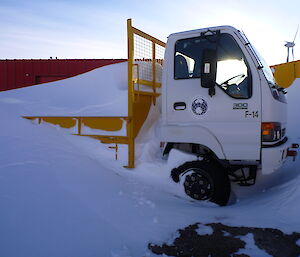 A truck which is largely buried under snow.