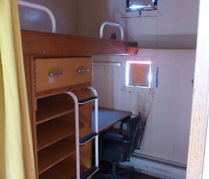 The one person room or donga with a raised bed with storage and a desk below.