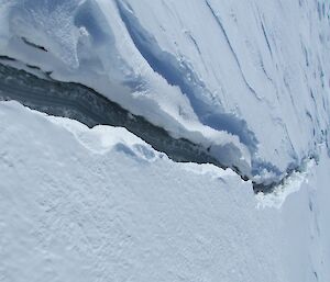 A crack leading off over the ice to a distant iceberg.