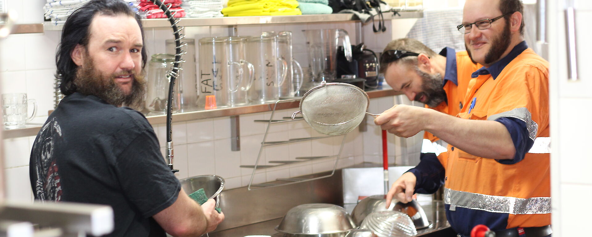 A couple of expert slushies at the sink with a load of dishes providing advice on how to clean them.