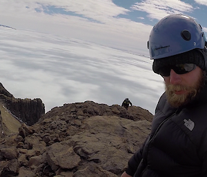 Two expeditioners on the top of a peak, with clouds all around them