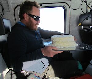 Matt balancing the cake on his knee while driving a vehicle