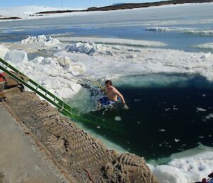 Angus going into the water with a safety rope tied to him, he descends a hole cut in the ice