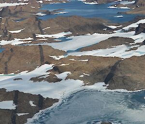 The Vestfold Hills, lots of bright blue small lakes with ice on top surrounded by dark brown rock hills