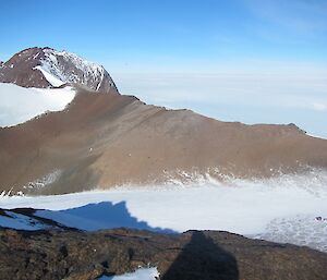 Panoramic picture of a large steep mountain with a dusting of snow