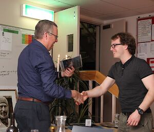 Station Leader shaking the hand of an expeditioner and handing over a midwinter medal