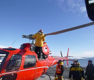 One engineer attaching helicopter blades to a B3 while 3x other men watch