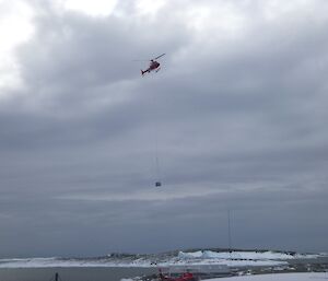 A B3 helicopter with a slingloaded cage pallet underneath