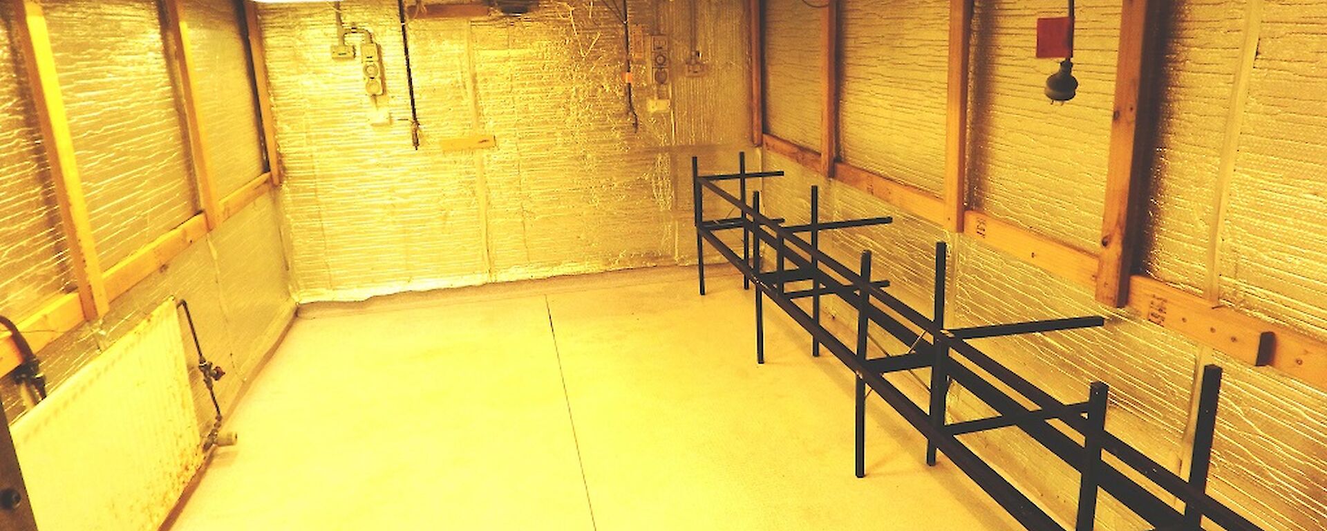 A large room lined with aluminium insulation with a black metal stand in corner