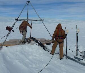 A steel prism with two men in harnesses working on it