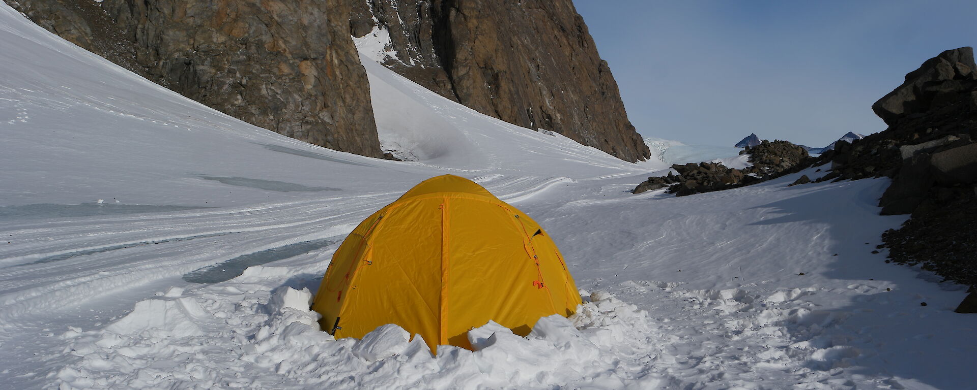 A little yellow tent set up in the snow