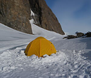 A little yellow tent set up in the snow