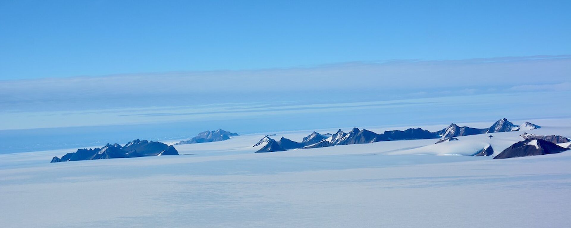 a series of mountain in the distance surrounded by snow