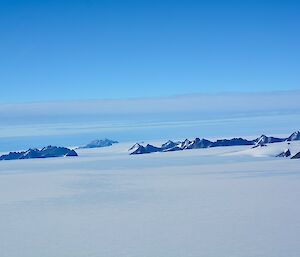 a series of mountain in the distance surrounded by snow