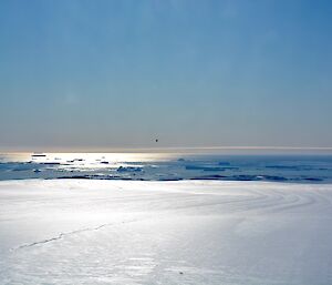 Looking across a glacier to the ocean in the distance with lots of icebergs