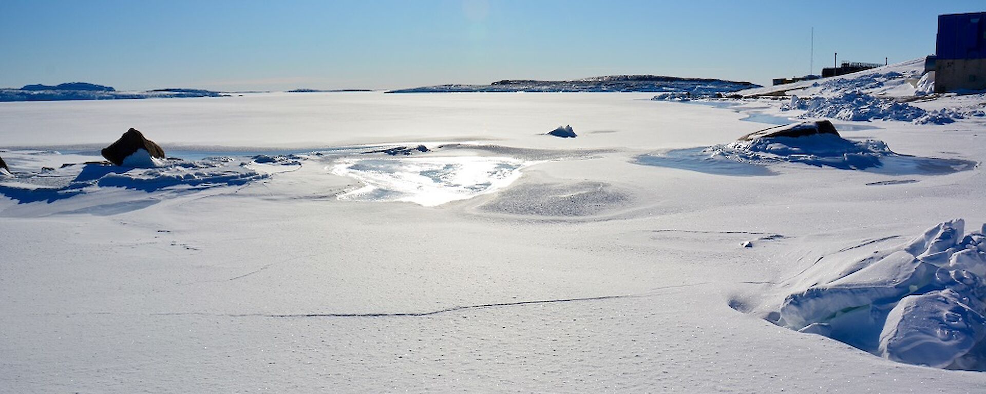 A horseshoe shaped harbour full of sea ice and covered in snow