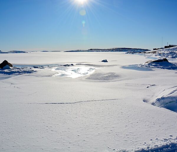 A horseshoe shaped harbour full of sea ice and covered in snow