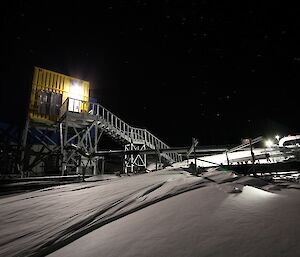 A yellow building with snow in front on a starry night