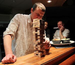 A man removing a block from the Jenga tower