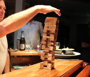 A man placing a block on top of a Jenga pile