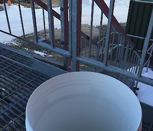 A white bucket of brine on a outside step