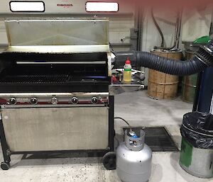 A BBQ hooked up to a large exhaust fan with piping