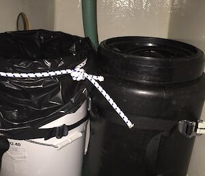 two buckets under a sink with a pipe leading to one