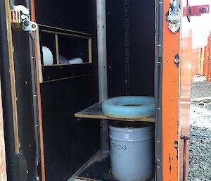 a bench seat with a toilet seat mounted on it and a bucket underneath